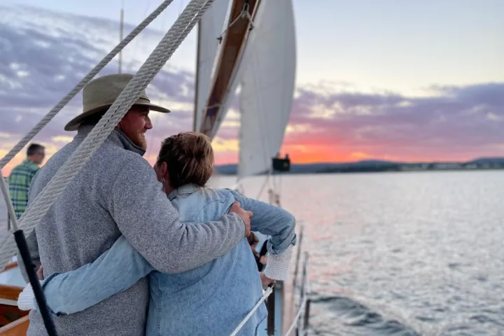 a man and a woman standing in front of a body of water