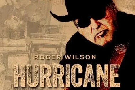 Man in hat playing guitar, text: 'Roger Wilson Hurricane'.